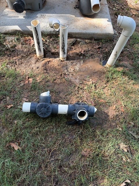 Broken pool plumbing pipes dug up before repair